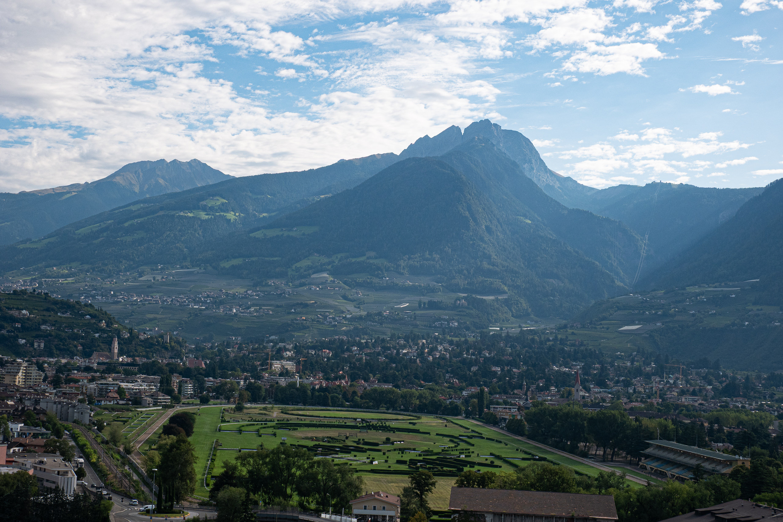 Blick über Meran und die Pferderennbahn zu den Bergen